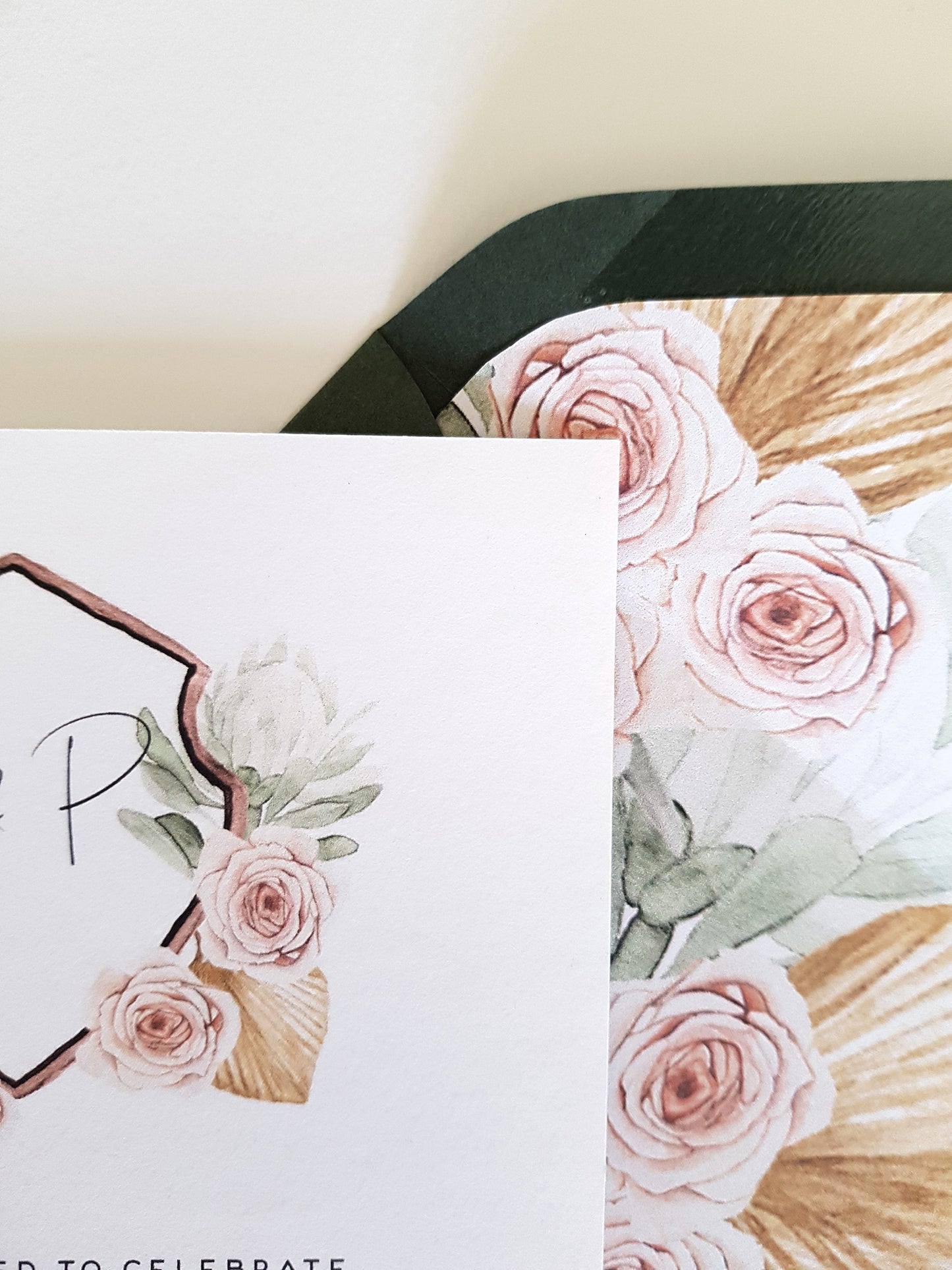Detailed image of the crest wedding design with dusty pink roses, green protea and tan tropical leaves